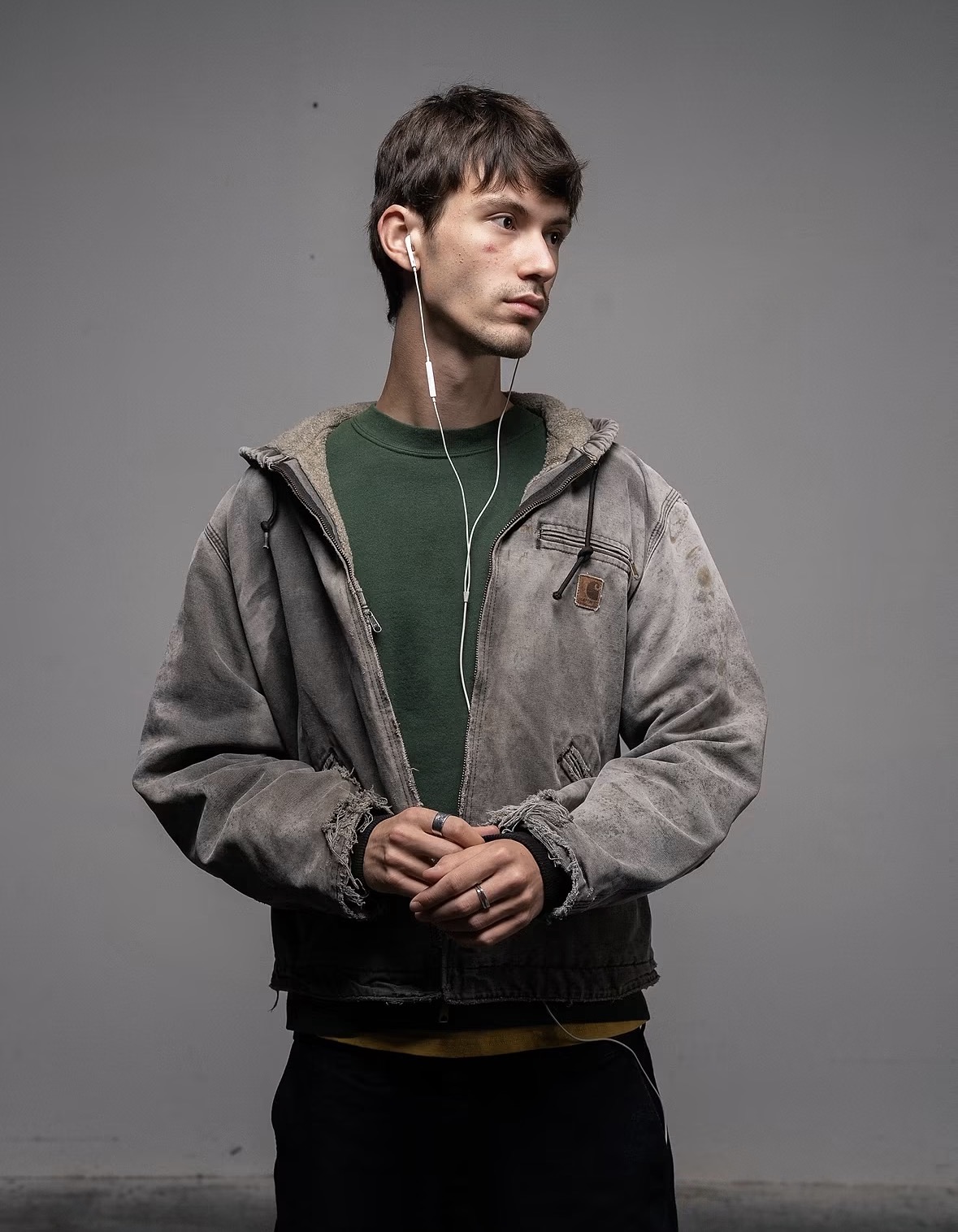 Fedor Uskov in a worn work jacket, wearing earphones and looking to the side